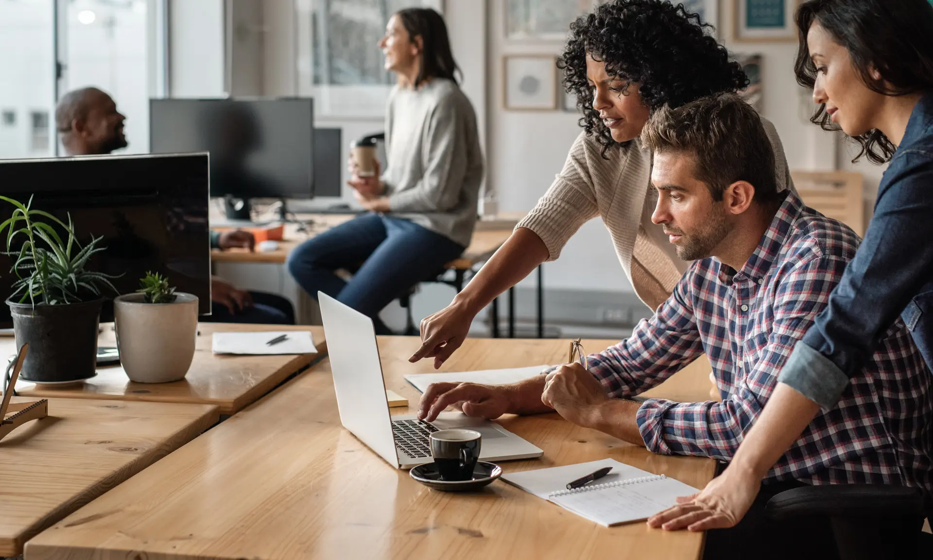 trois personnes regardant un ordinateur dans un espace de coworking